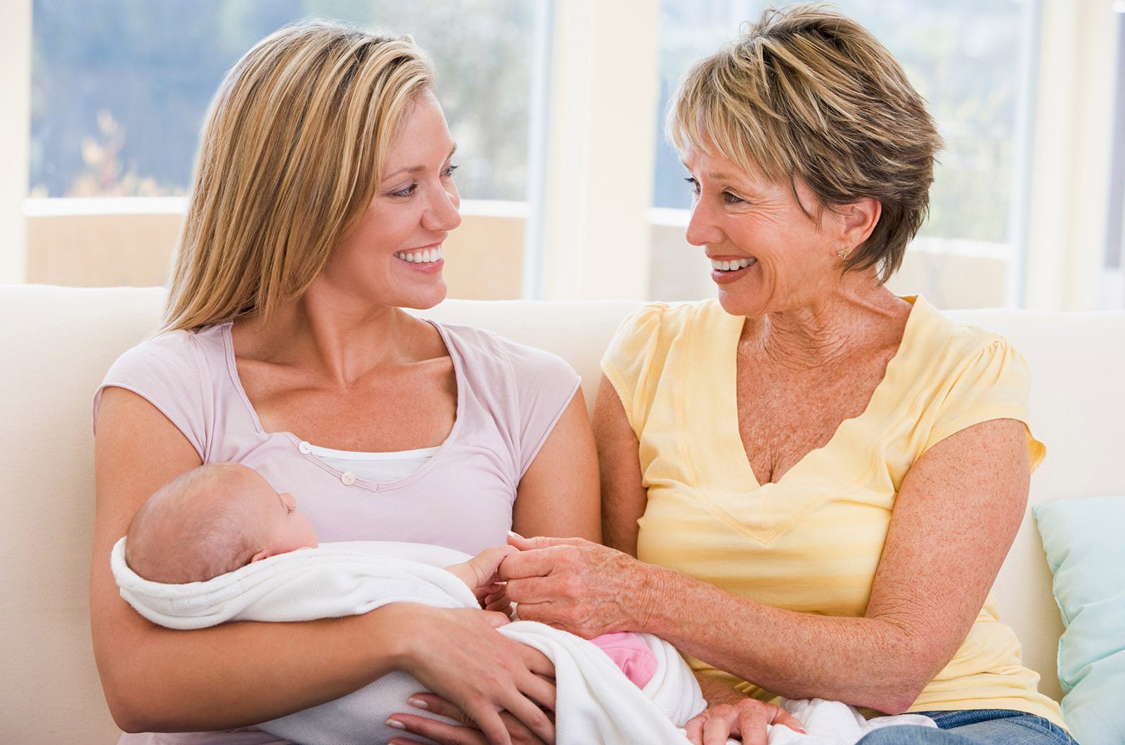 Grandmother and mother in living room with baby smiling
